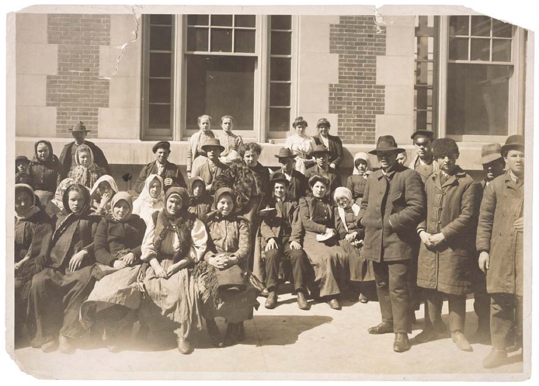 Et sort-hvidt foto af en gruppe immigranter uden for en bygning på Ellis Island