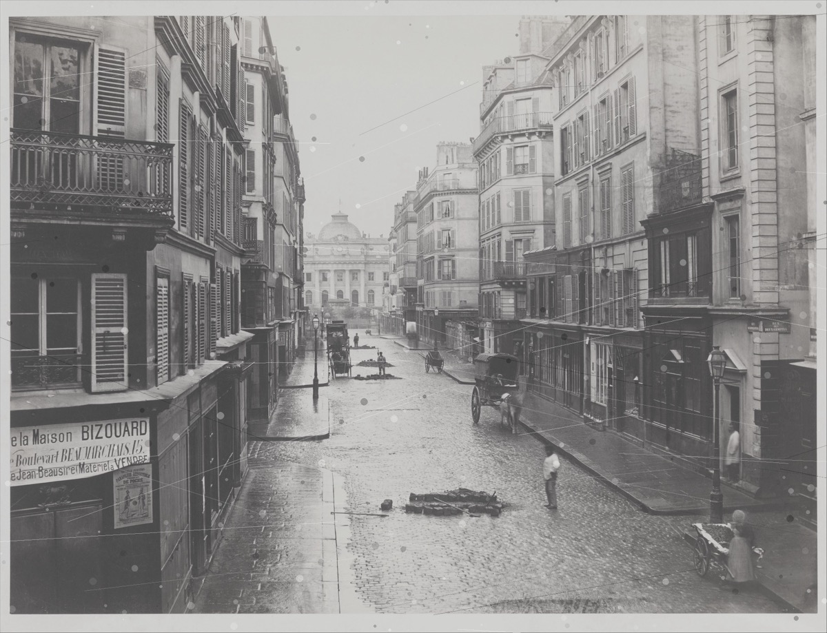 Un escaneo en blanco y negro arañado y de bajo contraste de una calle de París de la década de 1860